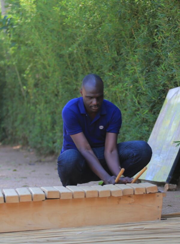Playing the amadinda, a traditional wooden xylophone, at Ewaffe Cultural Village