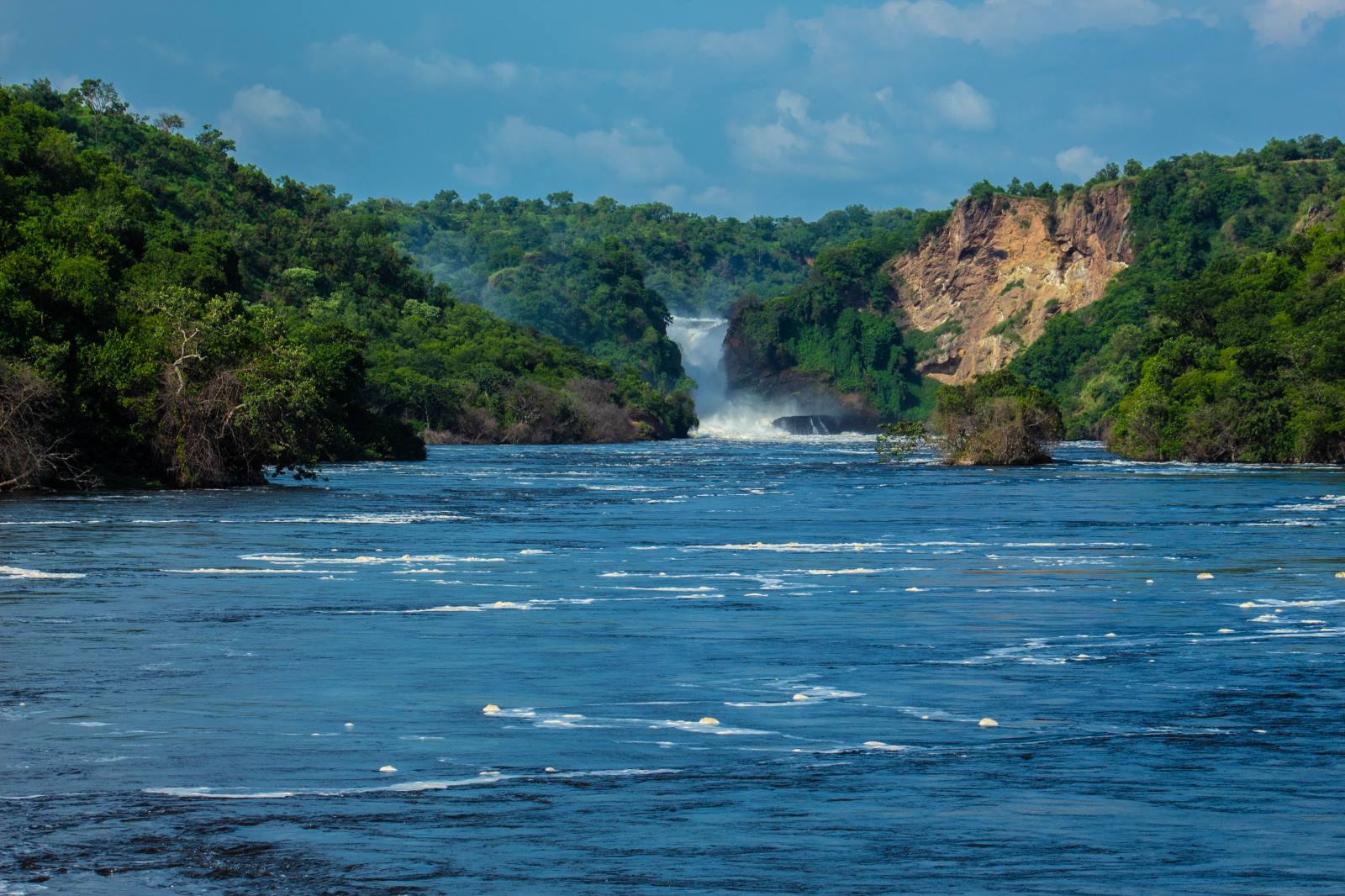 Murchison Falls pouring through a green gorge, seen from the wide river Nile, Uganda